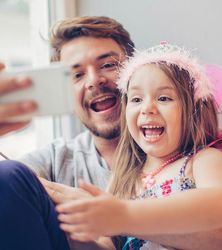 A father and his daughter smile and take a selfie